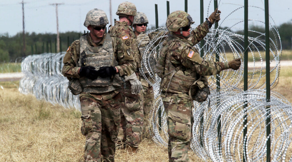 Militares estadounidenses instalando alambre de navajas en la frontera con México, como parte de un despliegue de seguridad.