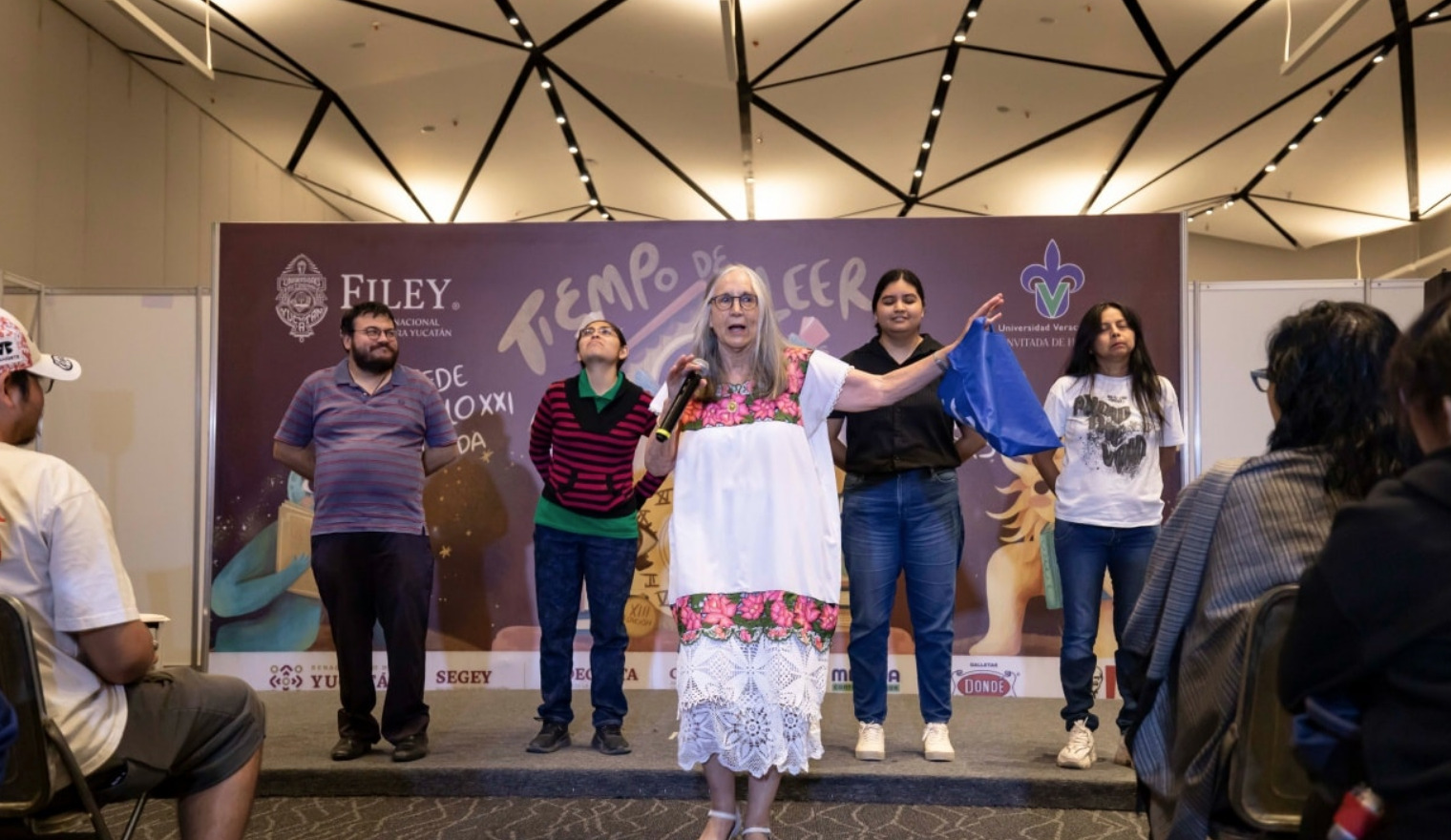 La científica Julieta Fierro dando una conferencia en la FILEY 2025, con un público y otros panelistas de fondo.