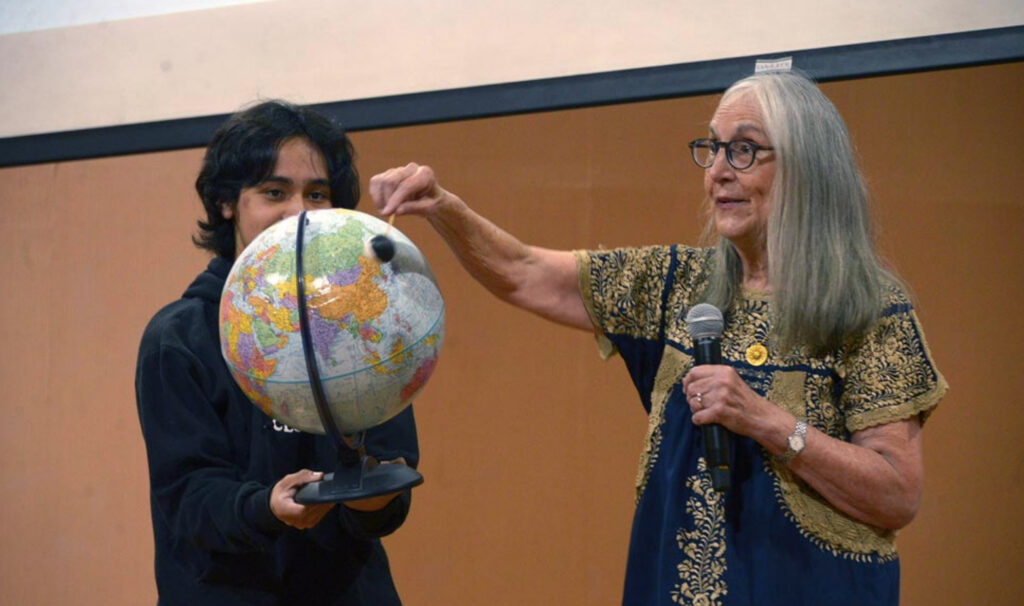 La científica Julieta Fierro interactuando con un joven y un globo terráqueo durante una conferencia en la UNAM.
