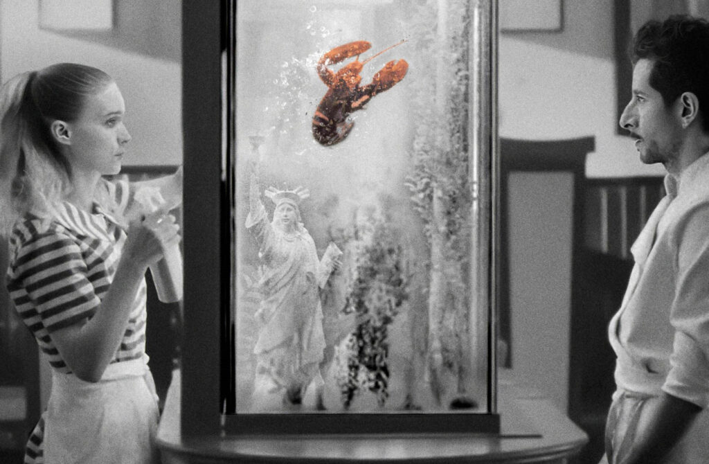 Fotograma de "La cocina", con una mujer, un hombre y una langosta en un tanque de agua, en blanco y negro.