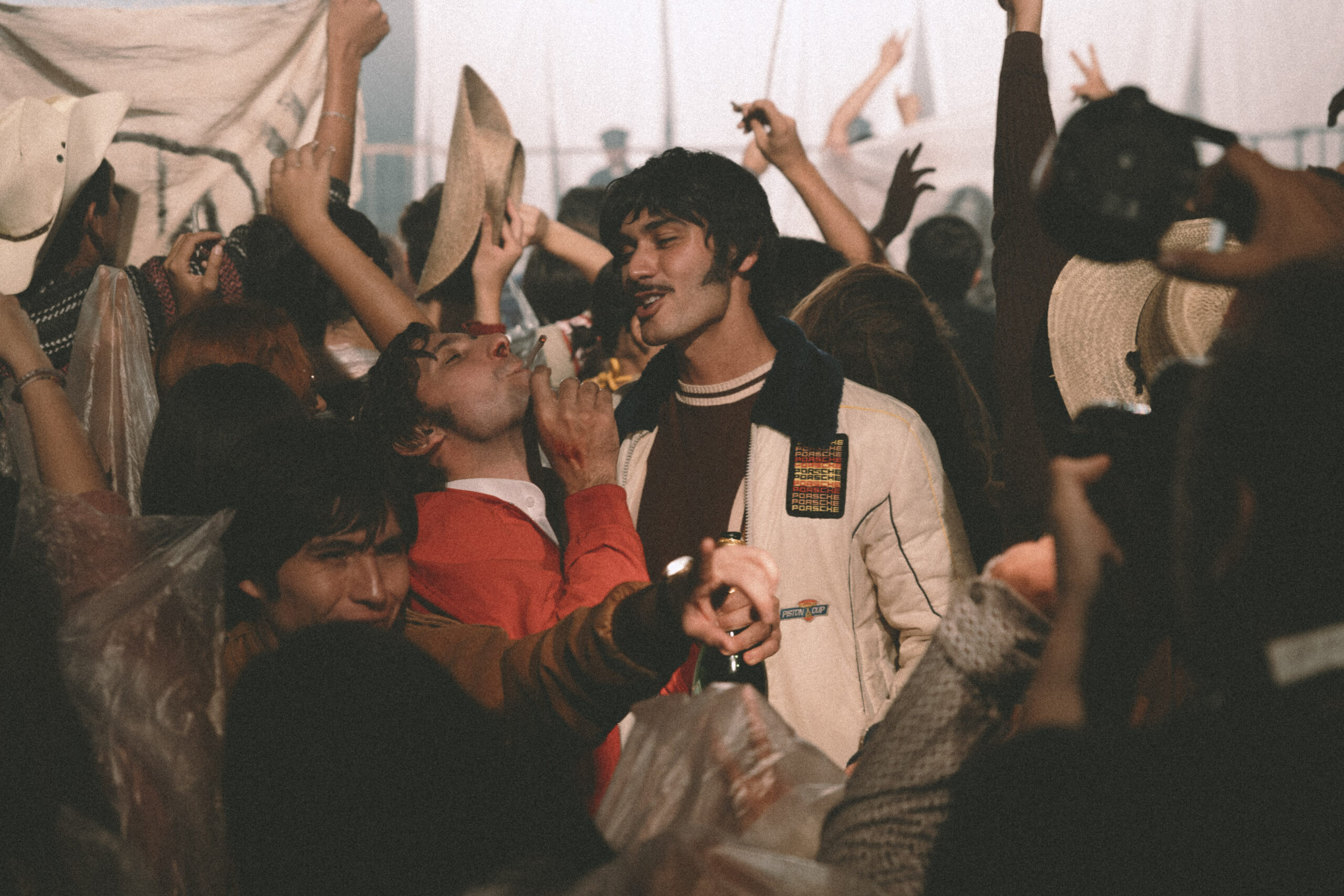 Fotograma de "Autos, Mota y Rocanrol", mostrando a Alejandro Speitzer y Emiliano Zurita en la multitud del Festival de Avándaro.