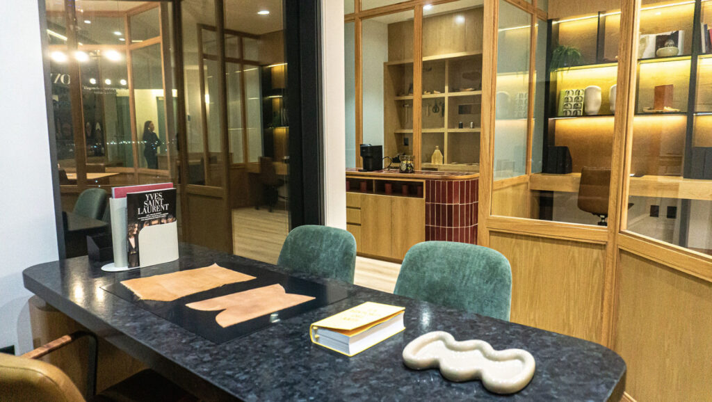 Sala de juntas o espacio ejecutivo dentro del coworking de Level Campestre León, con mesa oscura, sillas de terciopelo verde y mobiliario de madera con iluminación cálida.