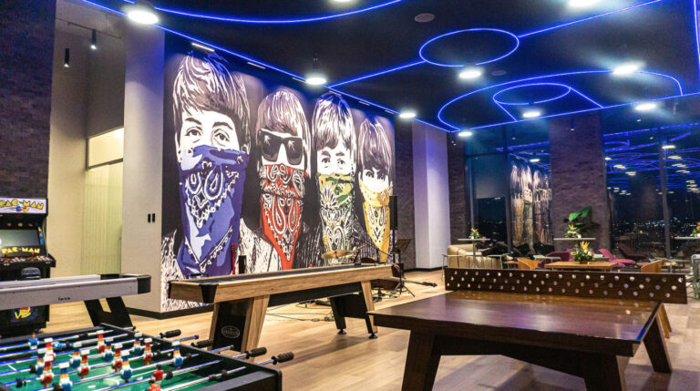 Área de entretenimiento de Level Campestre León, con un mural pop de los Beatles y una zona de juegos y música.