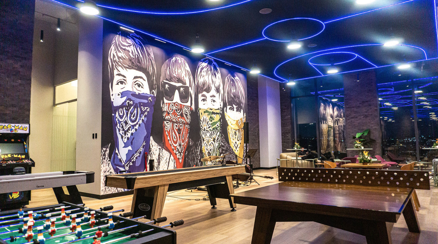 Área de entretenimiento de Level Campestre León, con un mural pop de los Beatles y una zona de juegos y música.