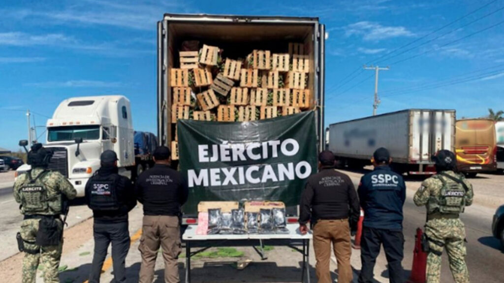 Mesa con paquetes de sustancias decomisadas, armas de fuego y equipo táctico bajo el resguardo de autoridades federales en la frontera norte.