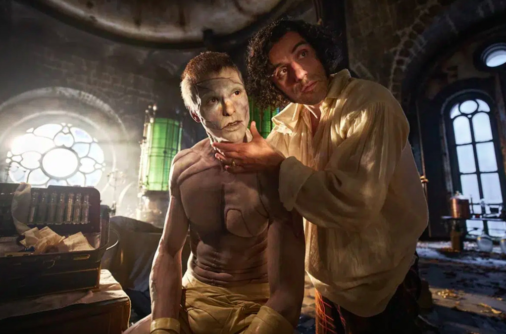 Oscar Isaac como Víctor Frankenstein examinando el rostro de la criatura (Jacob Elordi) en un laboratorio gótico detallado con frascos de reactivos verdes.
