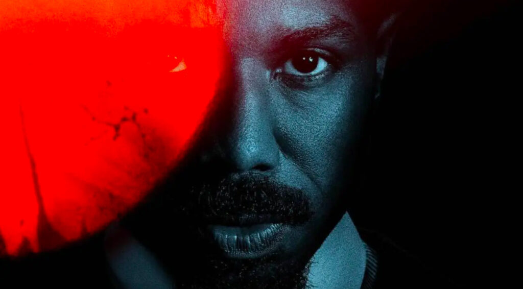 Retrato en primer plano de Michael B. Jordan con iluminación dramática en tonos azulados y una mancha roja intensa cubriendo parte de su rostro.