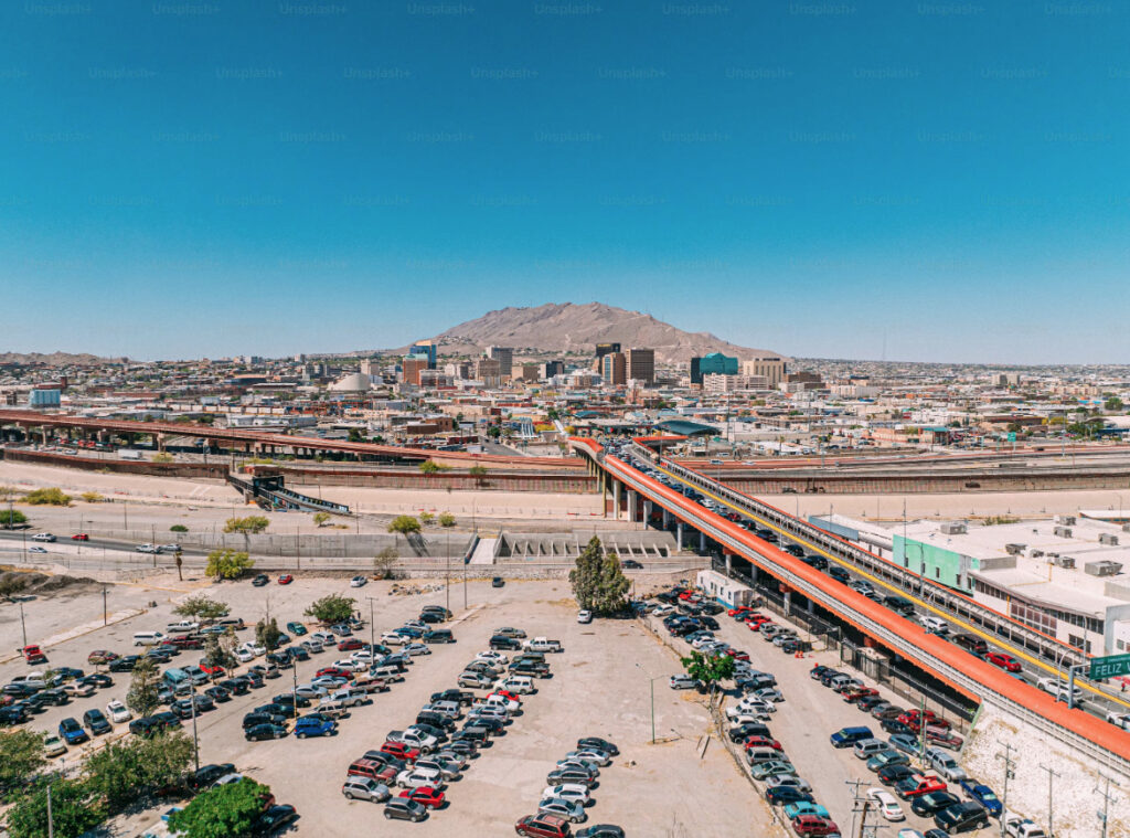 Vista aérea del Puente Internacional Paso del Norte con una larga fila de vehículos cruzando la frontera entre Ciudad Juárez, México, y El Paso, Texas, junto al muro fronterizo.