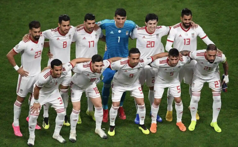 Foto de equipo de la selección nacional de fútbol de Irán posando en el campo, con uniformes blancos y el portero de azul.