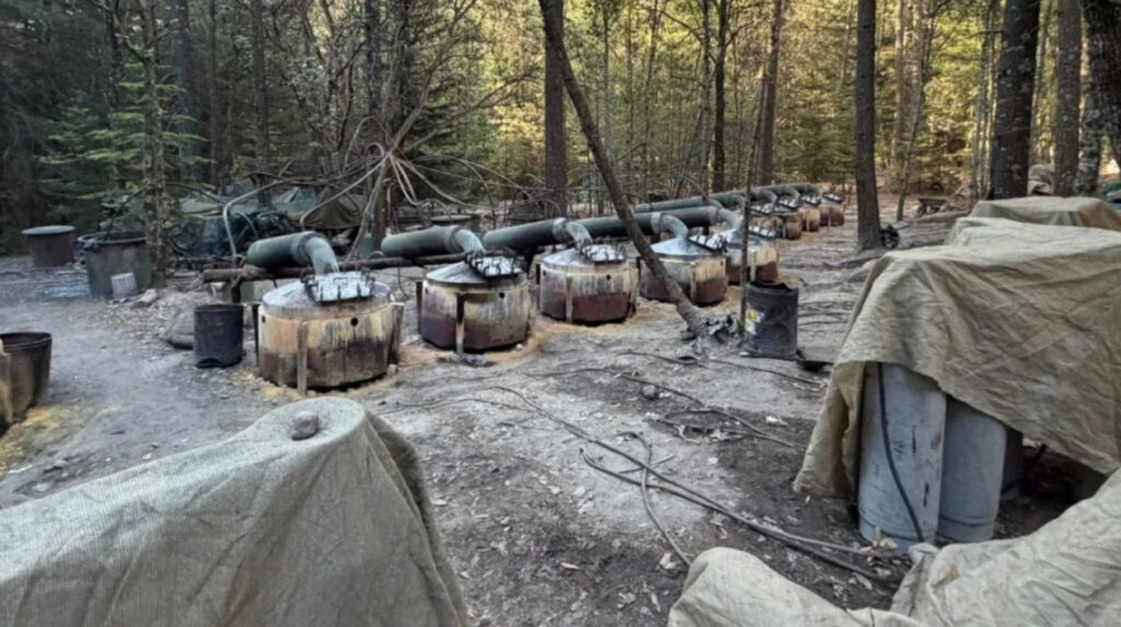 Interior de un enorme laboratorio clandestino en Chihuahua con múltiples tanques de gas, tambos de precursores químicos y depósitos bajo una estructura de lámina.