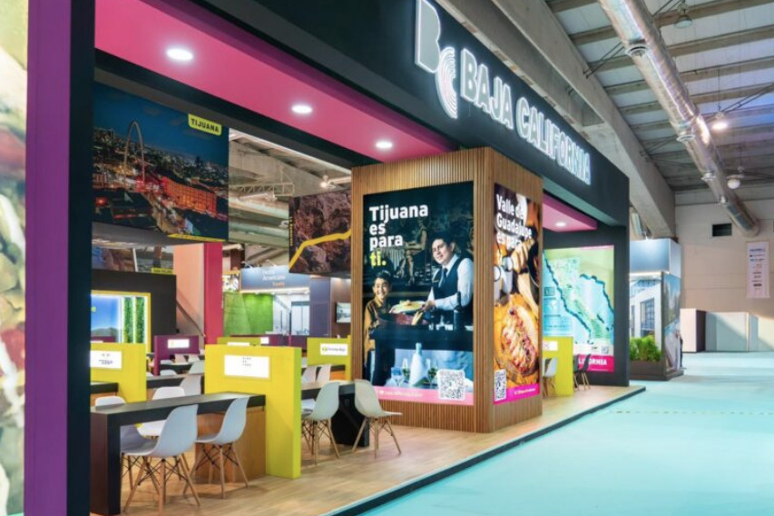Estructura moderna del pabellón de Baja California en el Tianguis Turístico de Acapulco, mostrando grandes pantallas con imágenes de paisajes regionales y áreas de reuniones de negocios.