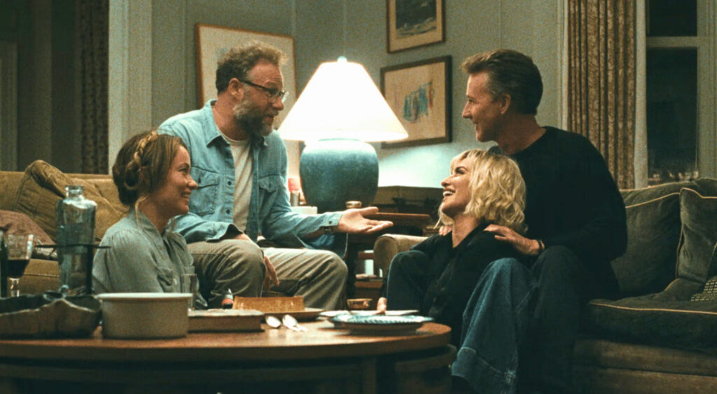 Un fotograma de la película 'The Invite' dirigida por Olivia Wilde, mostrando a cuatro actores, incluidos Seth Rogen con gafas, charlando en un salón de una cena de gala.