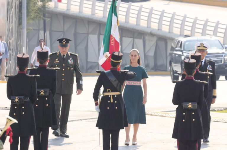 La presidenta Claudia Sheinbaum durante la ceremonia del 164 aniversario de la Batalla de Puebla, rodeada por elementos del Ejército Mexicano y escoltada por la bandera nacional.