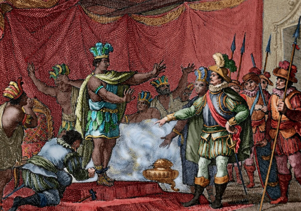 Grabado histórico coloreado que representa el encuentro entre el conquistador español Hernán Cortés, con armadura, y el emperador azteca Moctezuma II, con vestimenta de plumas, rodeados de sus respectivos séquitos.