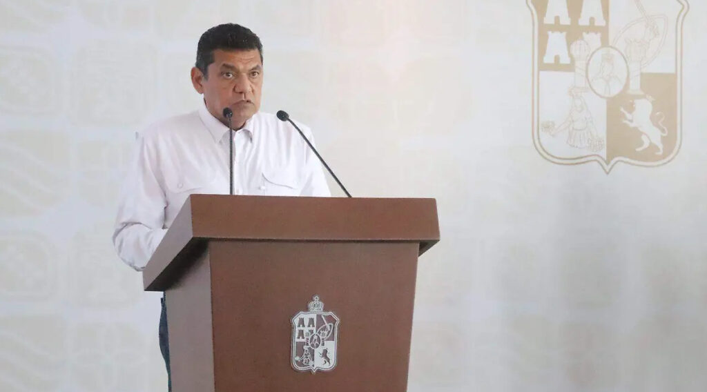El gobernador de Tabasco, Javier May, de pie tras un podio de madera con el escudo del estado, ofreciendo una conferencia de prensa oficial.