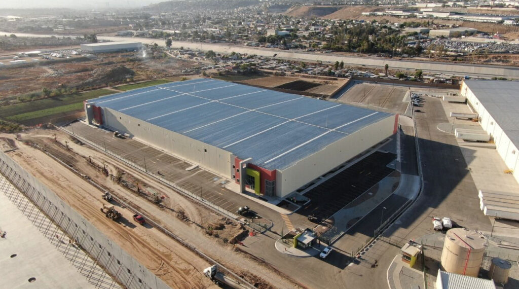 Vista aérea del Parque Industrial Alamar en Tijuana, mostrando grandes naves industriales, patios de maniobras y conexión vial en una zona de desarrollo tecnológico.