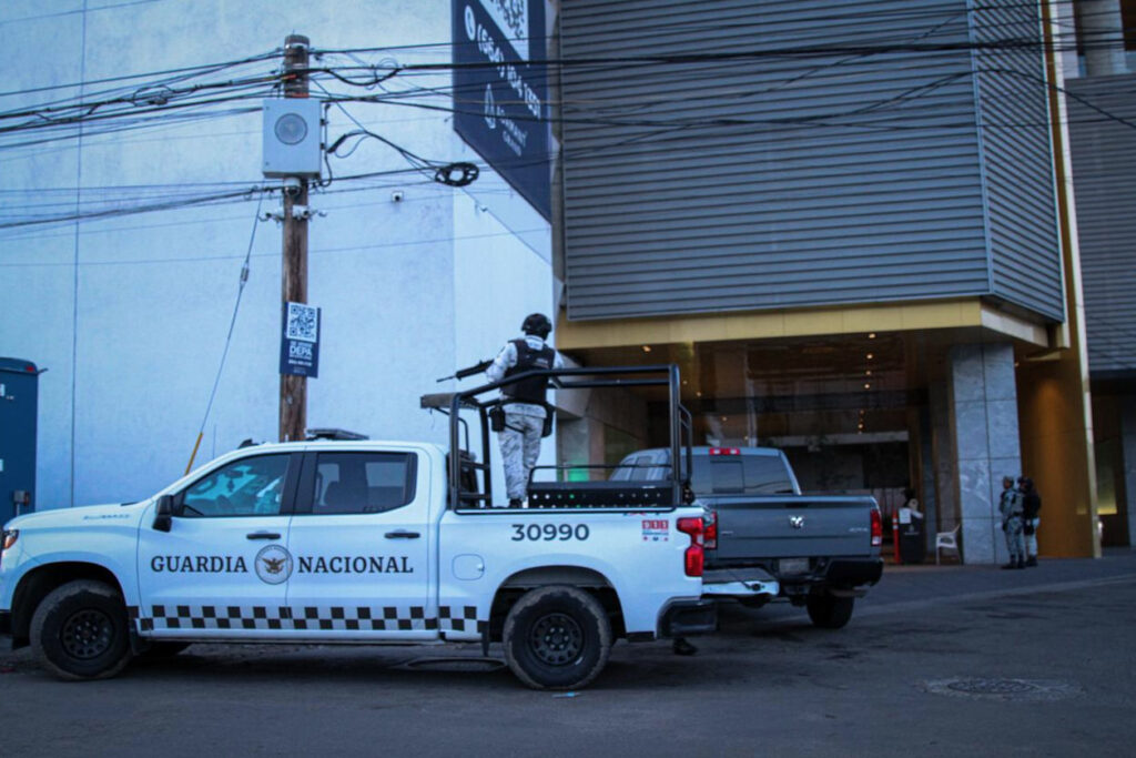 Patrullas y elementos de la policía municipal de Tijuana estacionados frente a la entrada del edificio Adamant Grand durante un operativo de seguridad.