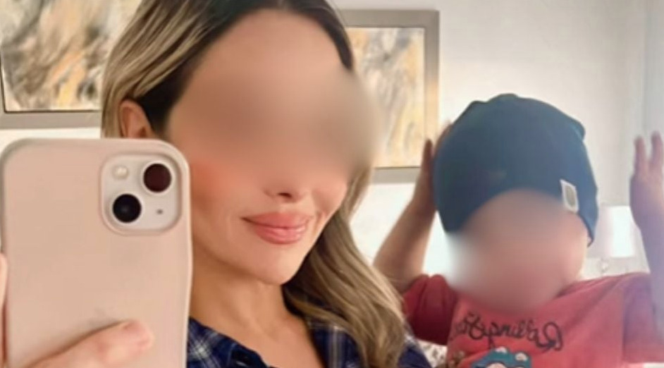 Fotografía tipo selfie de una mujer con el rostro difuminado sosteniendo un teléfono frente a un espejo, junto a un niño pequeño también con el rostro difuminado que lleva un gorro azul.