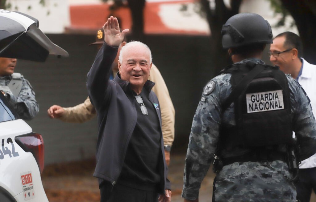 l exgobernador Ernesto Ruffo Appel sonríe y levanta el pulgar custodiado por elementos de la Guardia Nacional a su llegada a Ensenada.