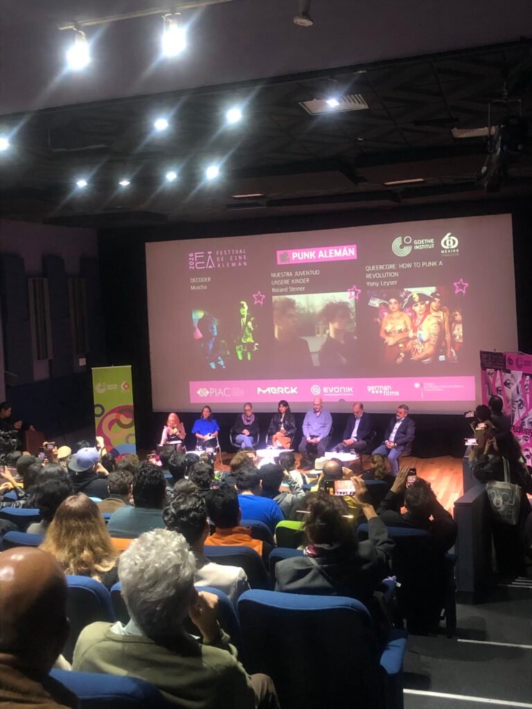 Presentación en pantalla de la retrospectiva Cine y punk diálogos de la disidencia durante la rueda de prensa del Festival de Cine Alemán con títulos de películas punk proyectados al fondo.