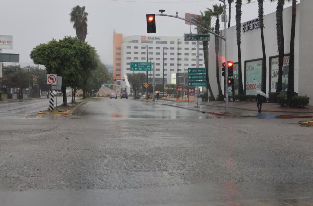 Avenida mojada con encharcamientos en Zona Río Tijuana cerca del cruce Sánchez Taboada durante un día de lluvia.