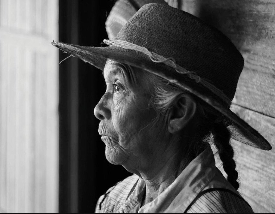 Retrato de perfil en blanco y negro de una mujer adulta mayor con sombrero en una escena de la película La reserva, dirigida por Pablo Pérez Lombardini.