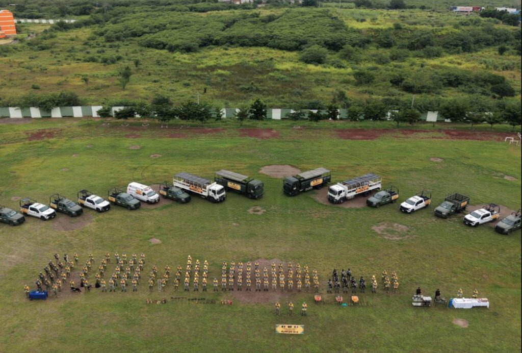 Elementos del Ejército Mexicano y vehículos oficiales formados en un campo verde para aplicar el Plan DN-III-E ante lluvias en Veracruz.