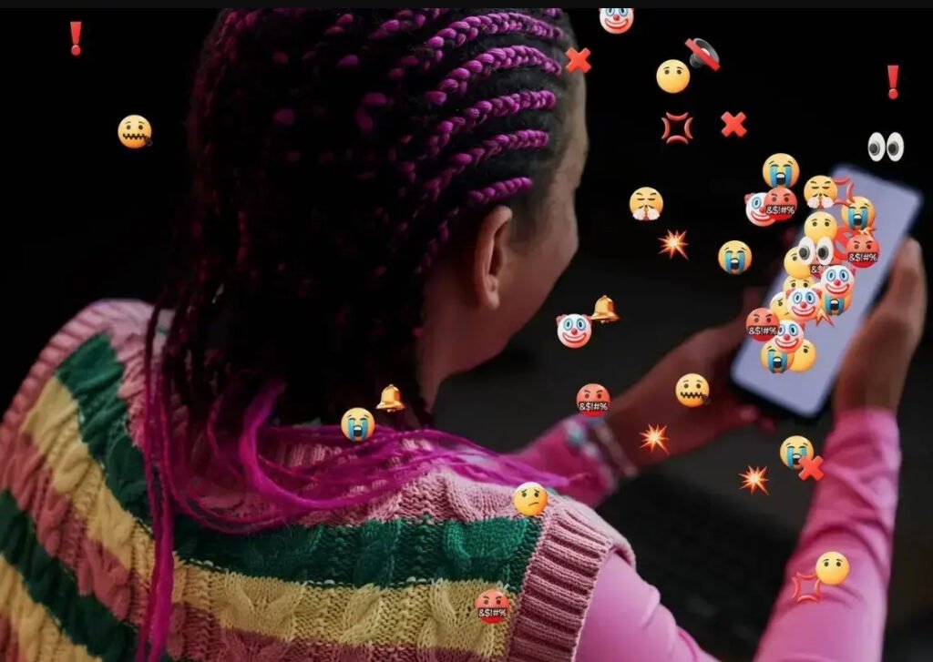 Joven utilizando un teléfono inteligente rodeada de emojis que representan ciberacoso, violencia y mensajes de odio en redes sociales.