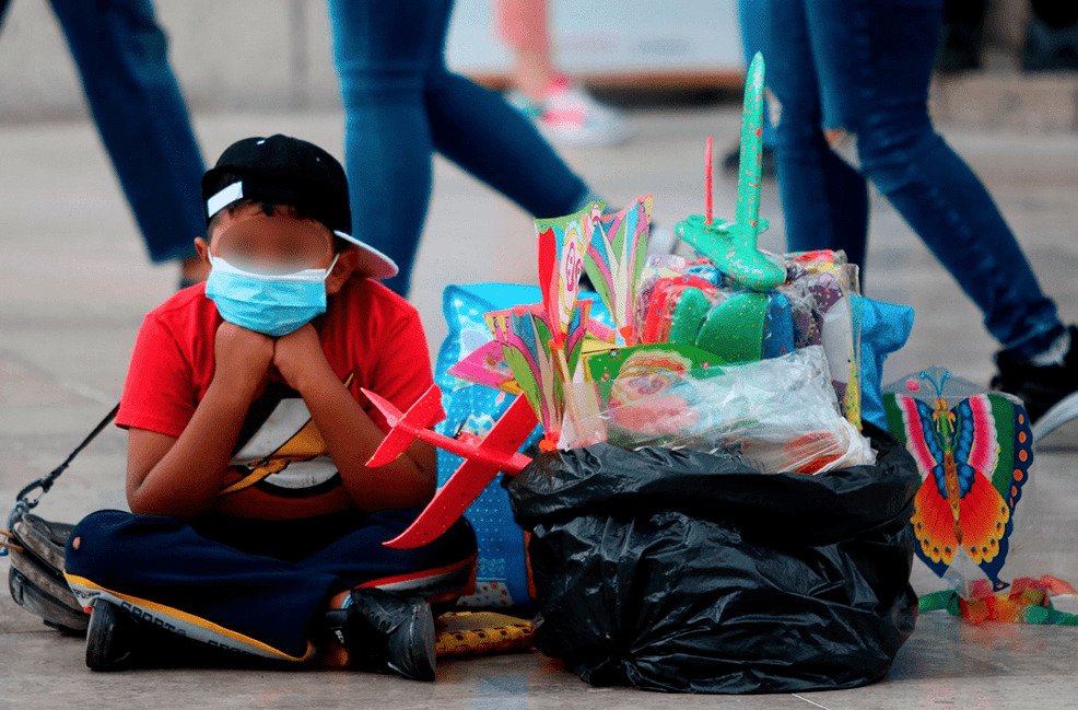 Niño sentado en la vía pública junto a una bolsa con juguetes y aviones de plástico en venta, representando el trabajo infantil en México según la ENTI 2025.